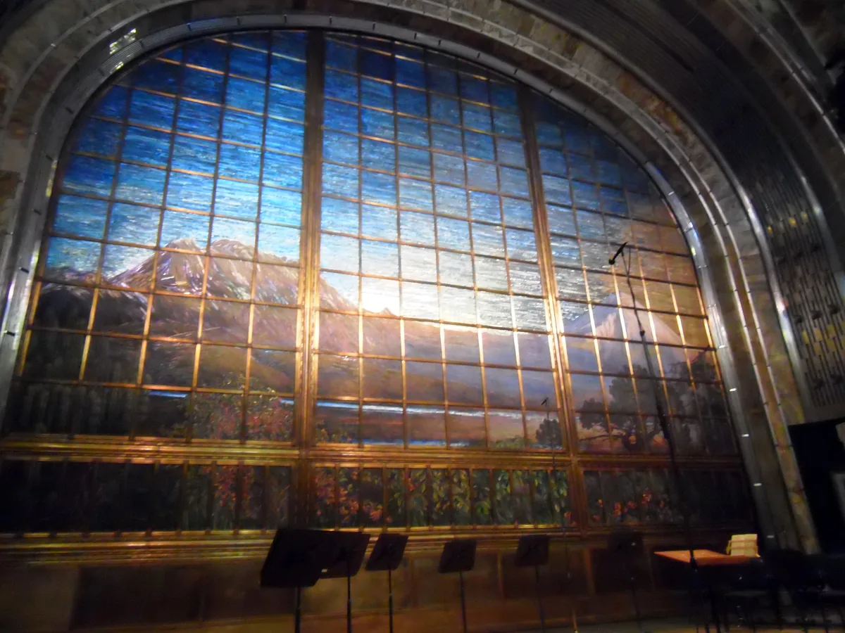 The Tiffany stained-glass stage curtain inside the Palacio de Bellas Artes' main theatre, a mosaic of the Valley of Mexico and its volcanoes set in an arched gold frame above the stage